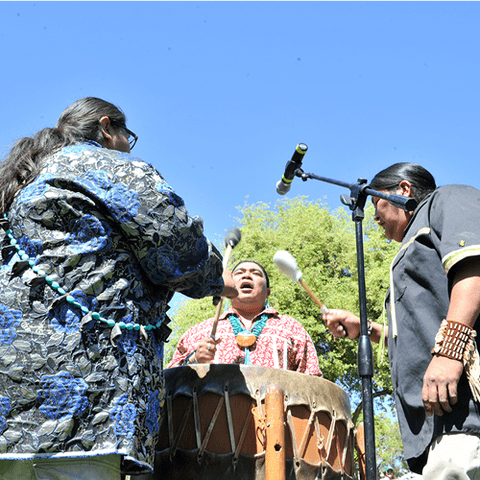 Three performers on a drum outside